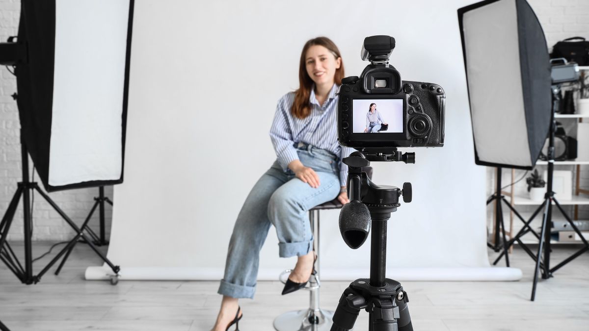 A headshot session in progress: the subject on a stool against white, lit by two softboxes, seen past the camera